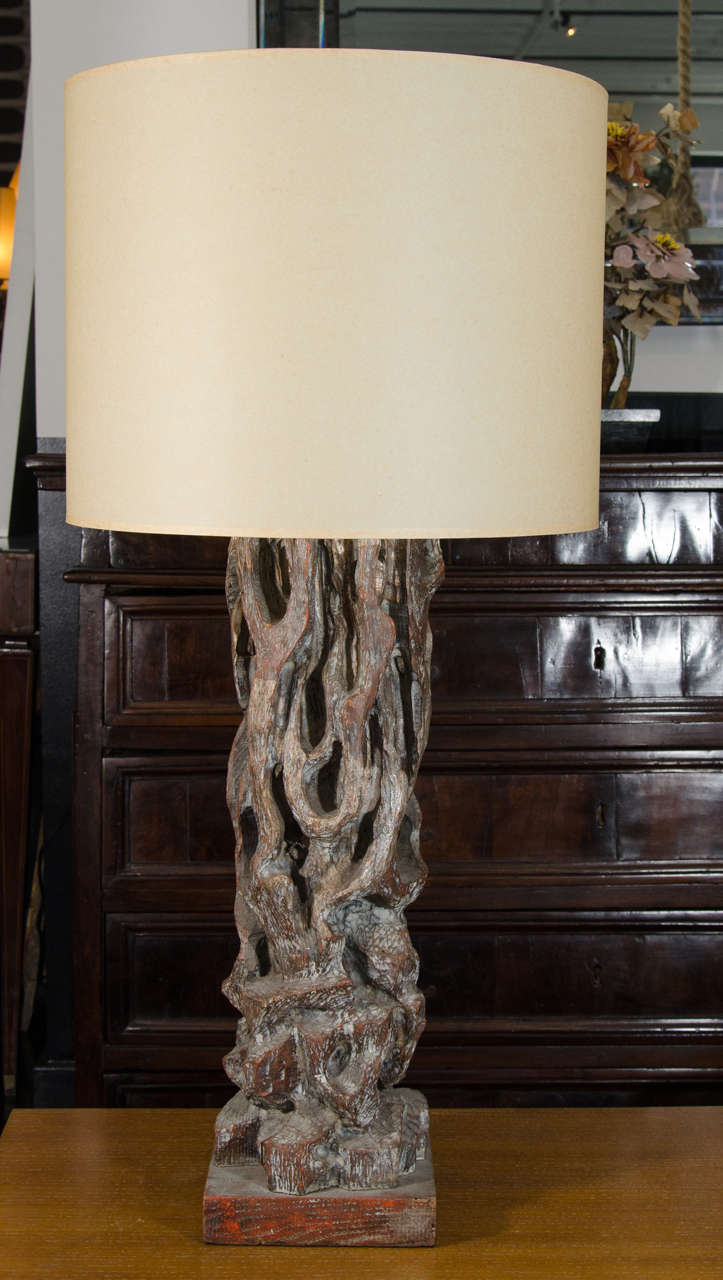 A carved wood lamp by James Mont. the lamp is deeply carved wood that resembles driftwood but with a stylish and subtle wash of gold leaf and burnt umber.
The lamp has a linen shade, it is tall and makes a big statement.