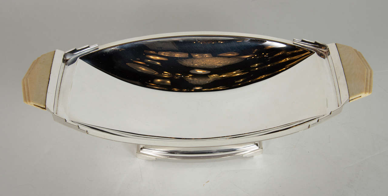 This gorgeous bowl features a stepped skyscraper style base with a plinth design with Art Deco ziggurat style lip with three tier ivory bakelite handles.This bowl would be great as just a decorative object,for serving or even in a powder room to put
