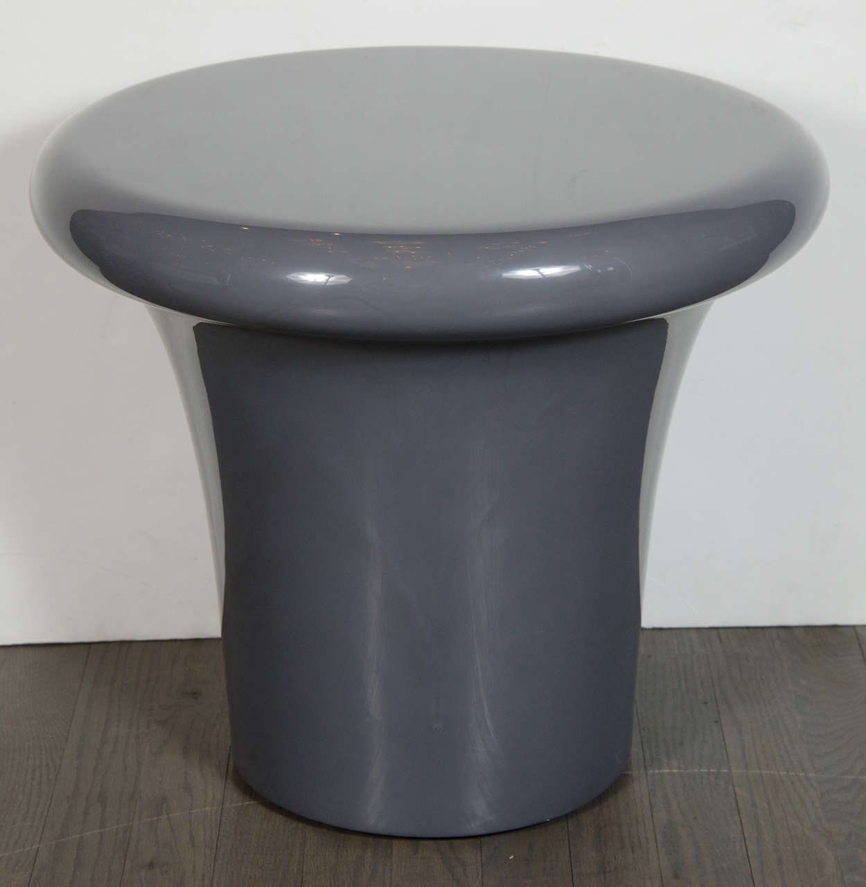 This Mid-Century side table features a subtly flared conical base opening into a round top with rounded edges and a dove gray lacquer finish. With its minimalistic organic form and radiant skein in a neutral hue, this piece illustrates furniture