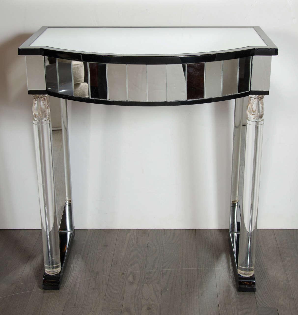 This stunning console table would be a great statement piece in any hallway or vestibule. It features a mirrored drawer and also has a stylized lucite column supports with a ebonized mahogany surround with a mirrored top. The lucite column supports