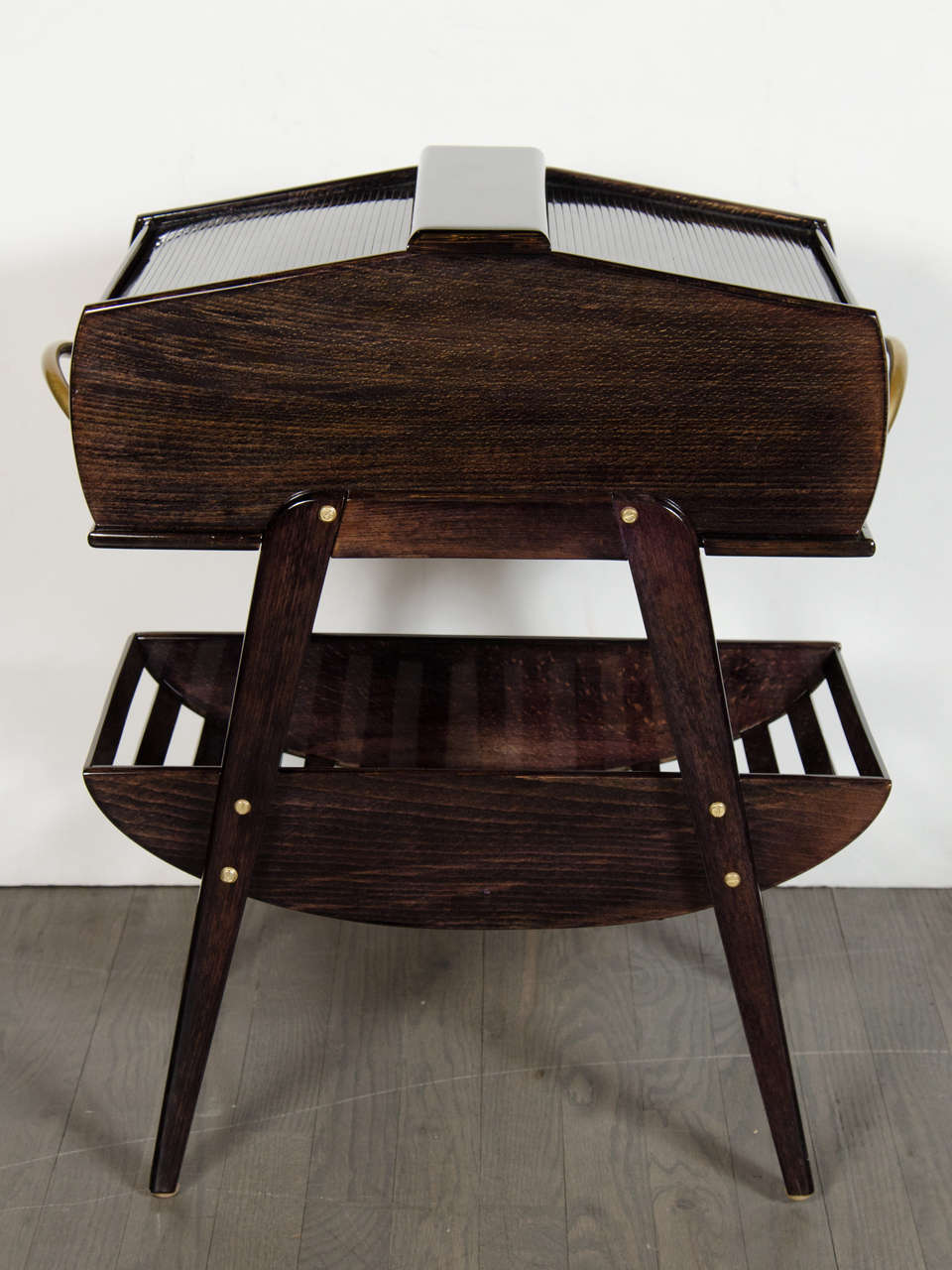 This beautiful Mid-Century Modern two-tier side table in ebonized walnut features a tambour top, a pull-out drawer on each side and stylized brass pulls. As you pull each drawer out from the sides, the top of the table on that drawers side opens to