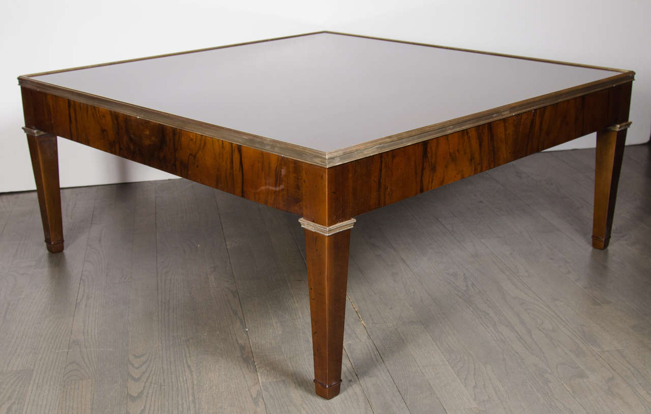 This handsome Mid-Century Modernist cocktail table has a square design in book-matched burled walnut bordered with a bronze trim which is carried over to the leg detail. It is generous in size with tapered legs and has been restored to mint