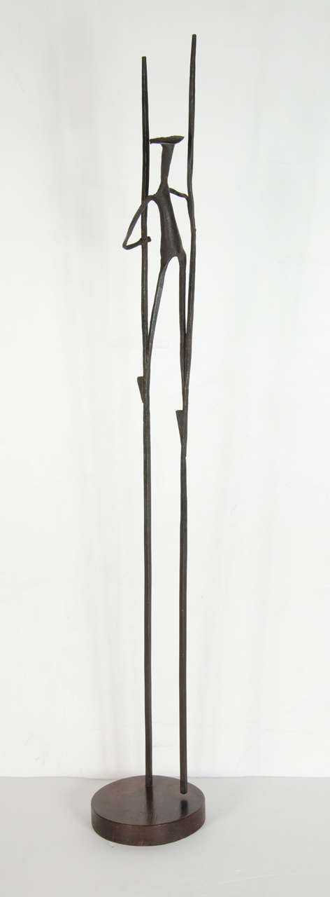 This hand wrought sculpture of welded steel features an abstract figurative design of a man on stilts.It is also mounted on a walnut base.