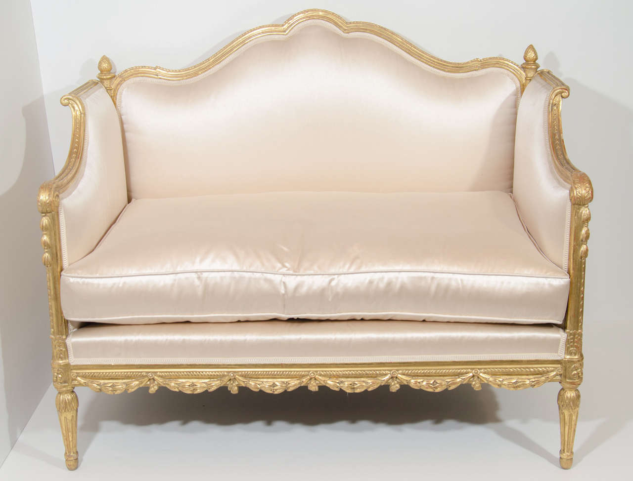 An exquisite and unique antique French Louis XVI style carved giltwood loveseats of superb craftsmanship upholstered in cream silk fabric with silk cushion.