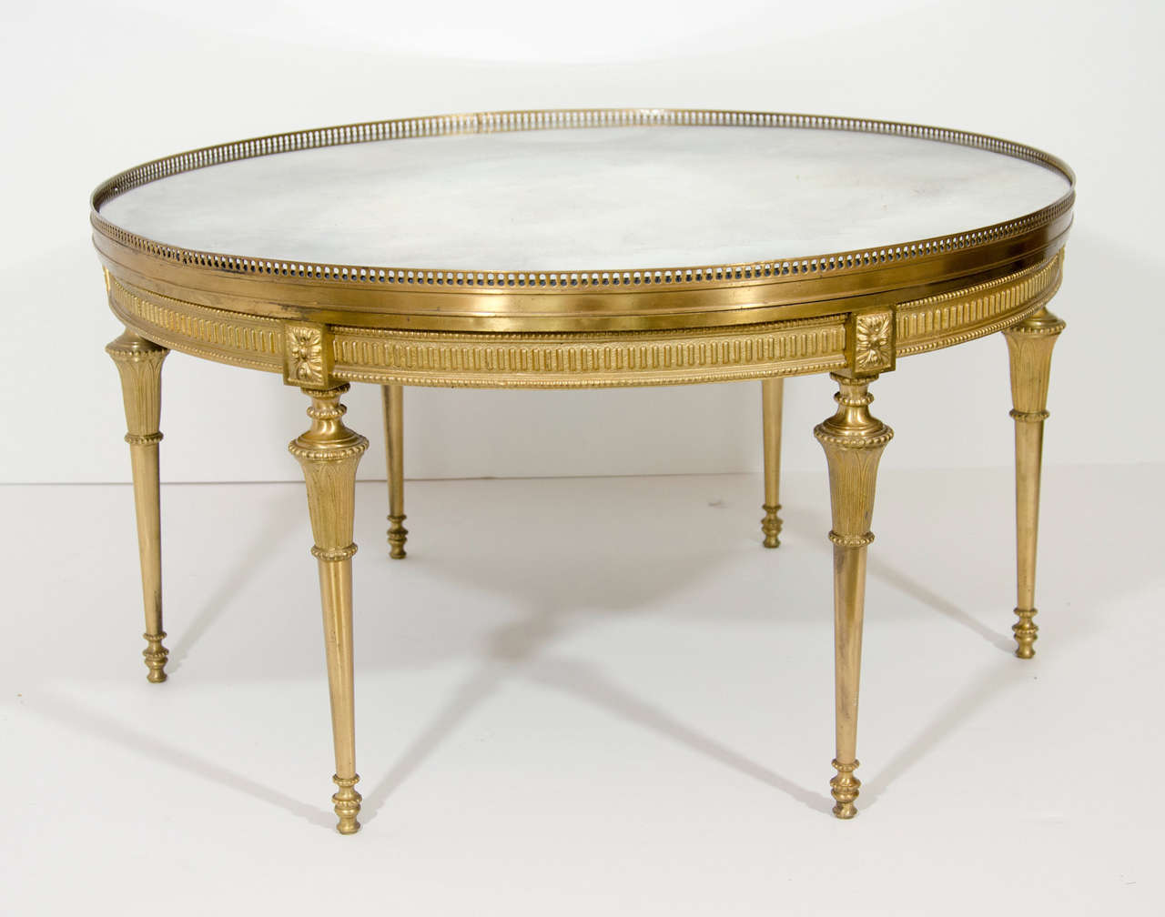 A circular antique French Louis XVI style gilt bronze mirror top coffee table of great quality embellished with reticulated gilt bronze gallery and gilt bronze legs.