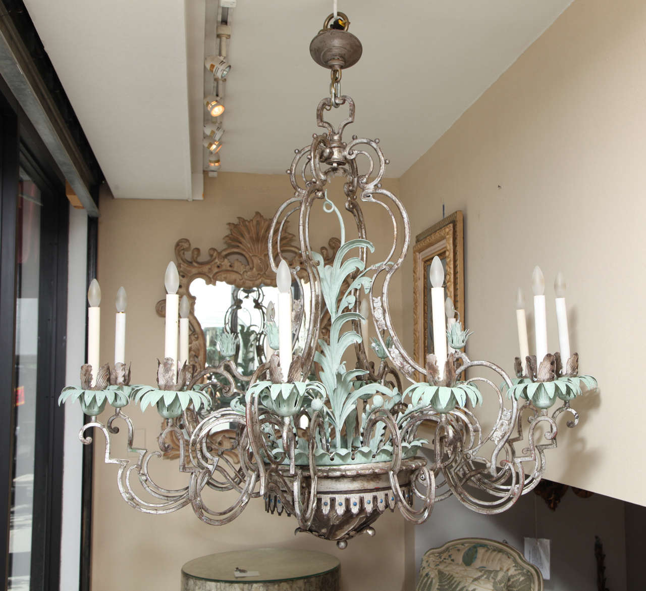 An American twelve-light silvered metal chandelier attributed to Maker Caldwell, the cage form center with palmette branch issuing from center dish with scalloped edge and repousse work on underside, each scroll form arm with bobeche having palmette