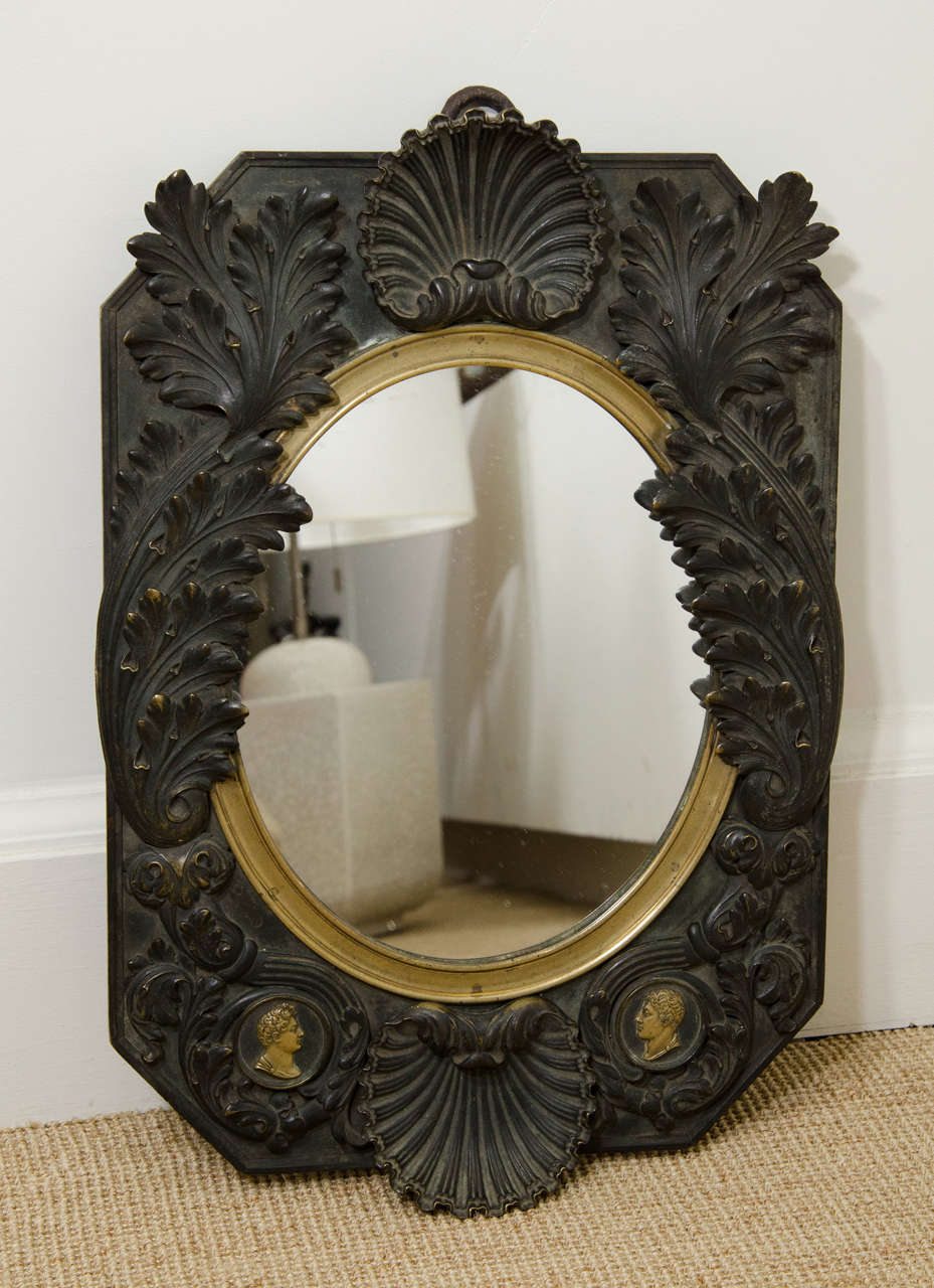 A 19th century French Empire bronze mirror with leaf and shell motif and Napoleon profile medallions at bottom quarter.
 