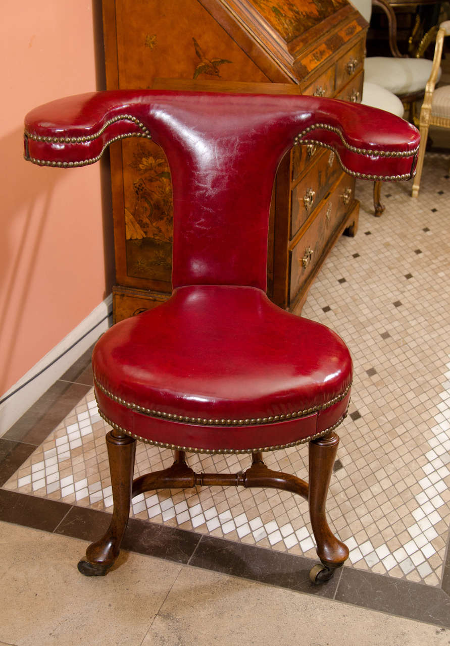 A rare Queen Anne mahogany Cock Fighting Chair with adjustable writing surface, turned stretchers and pad feet raised on brass castors.
