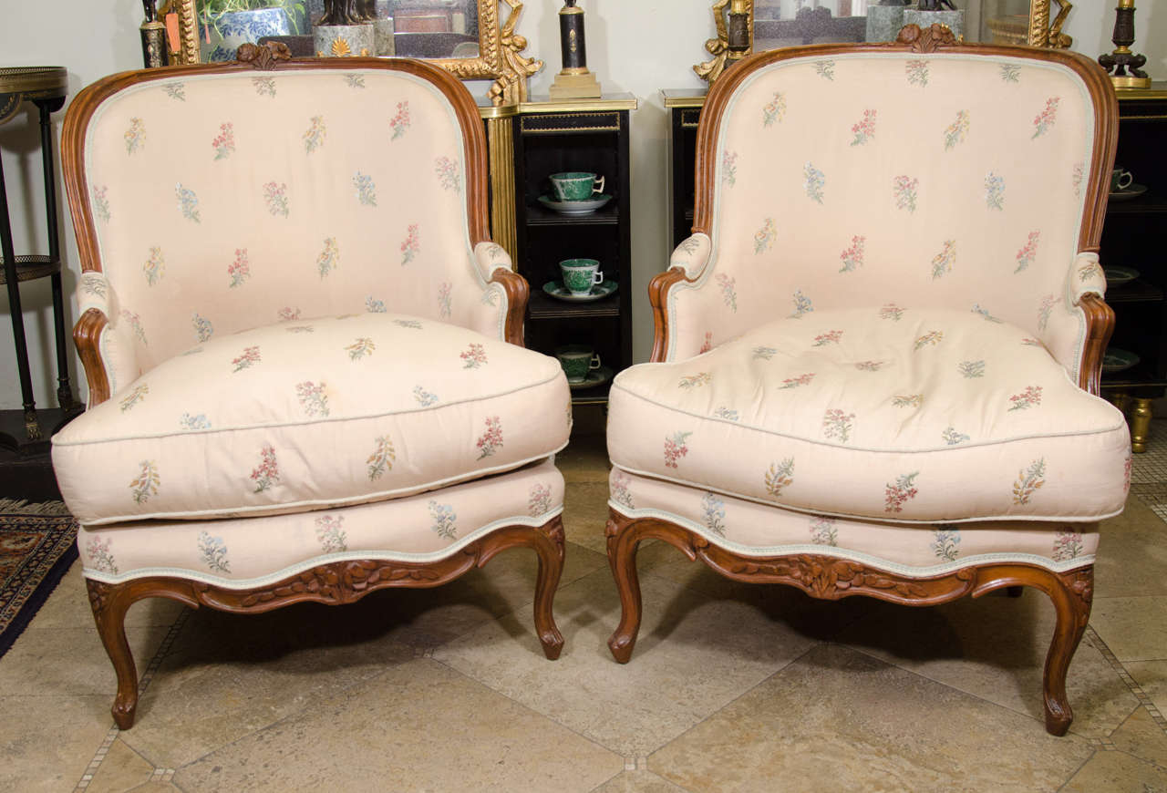 Pair of Louis XV tub bergeres with carved rosette crest and aprons.