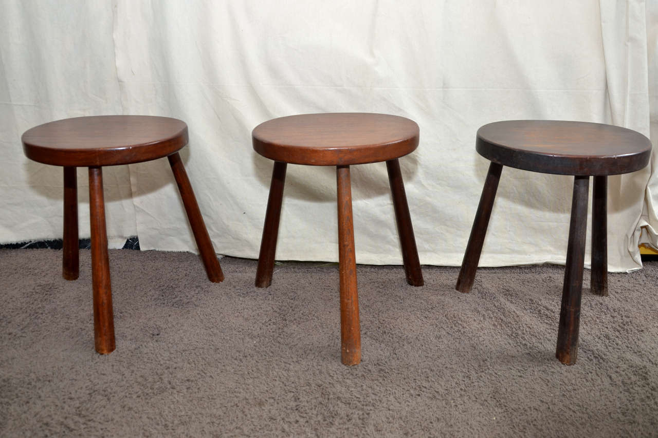 Three 1950s mahogany stools with three legs.