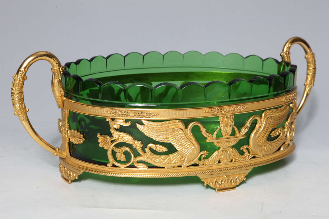 A fine Neoclassical/Empire gilt bronze and green glass centerpiece. In the middle of the centerpiece, intricately detailed gilt bronze swan handles and swans drink from a fountain on each side of the piece.  All of the bronze elements have finely
