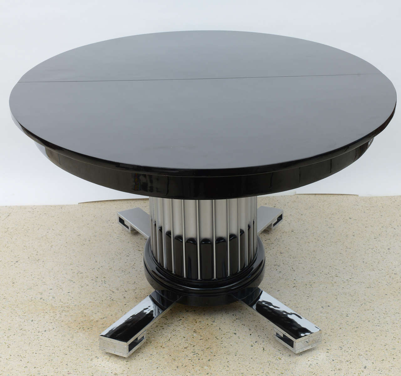 The black lacquer top with two leaves above a fluted oval pedestal with cream lacquer and silver gilt above a polished nickel base
extends with two 14