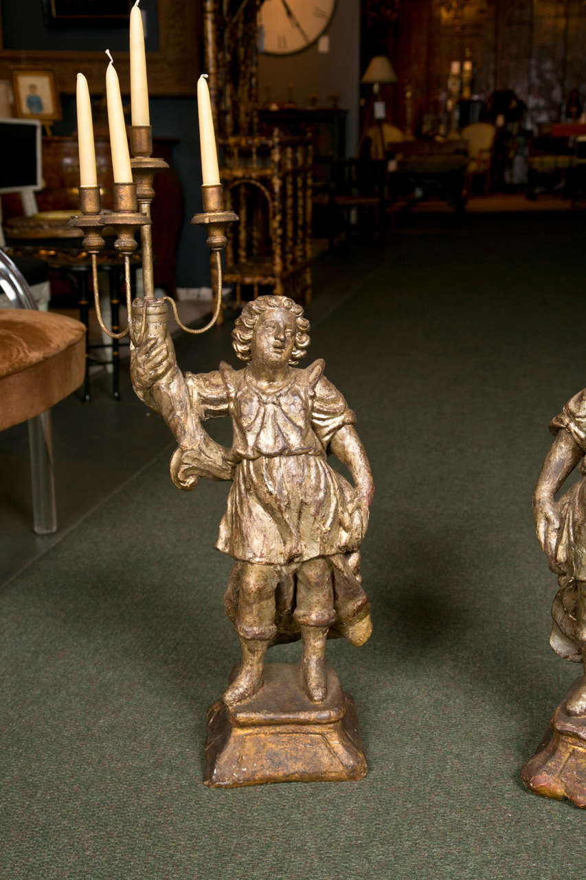 A pair of 18th century Italian carved figural, silver-gilt candelabra each with a four-candle arm.