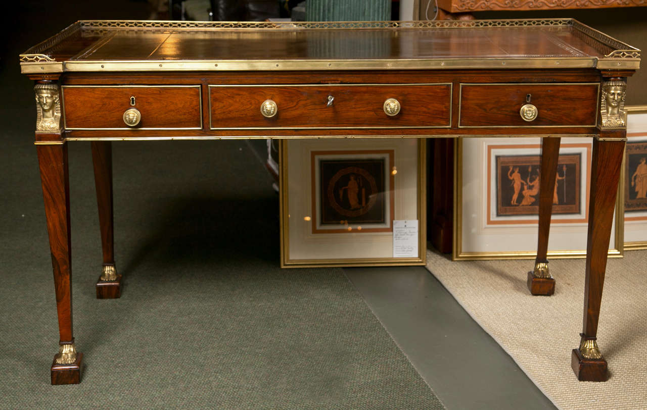 An early 19th century, French Empire rosewood and gilt bronze-mounted desk with a tooled leather writing surface in the Egyptian Revival style.