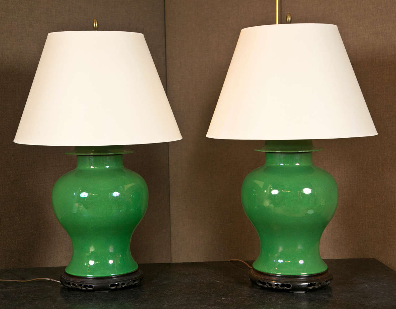 A pair of green-glazed Chinese porcelain ginger jars mounted as table lamps on carved wooden stands.