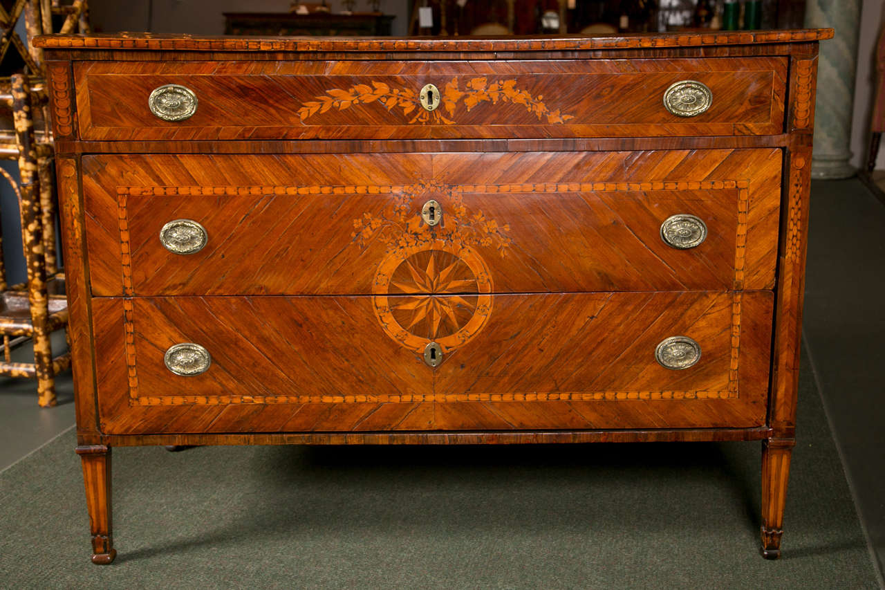 An 18th century Italian, Neoclassical commode from the area of Lombardy,  possibly Milan.  Decorated with pinwheel marquetry and floral inlay.  Inlays of walnut, kingwood, rosewood and cherry over a pine poplar carcass.