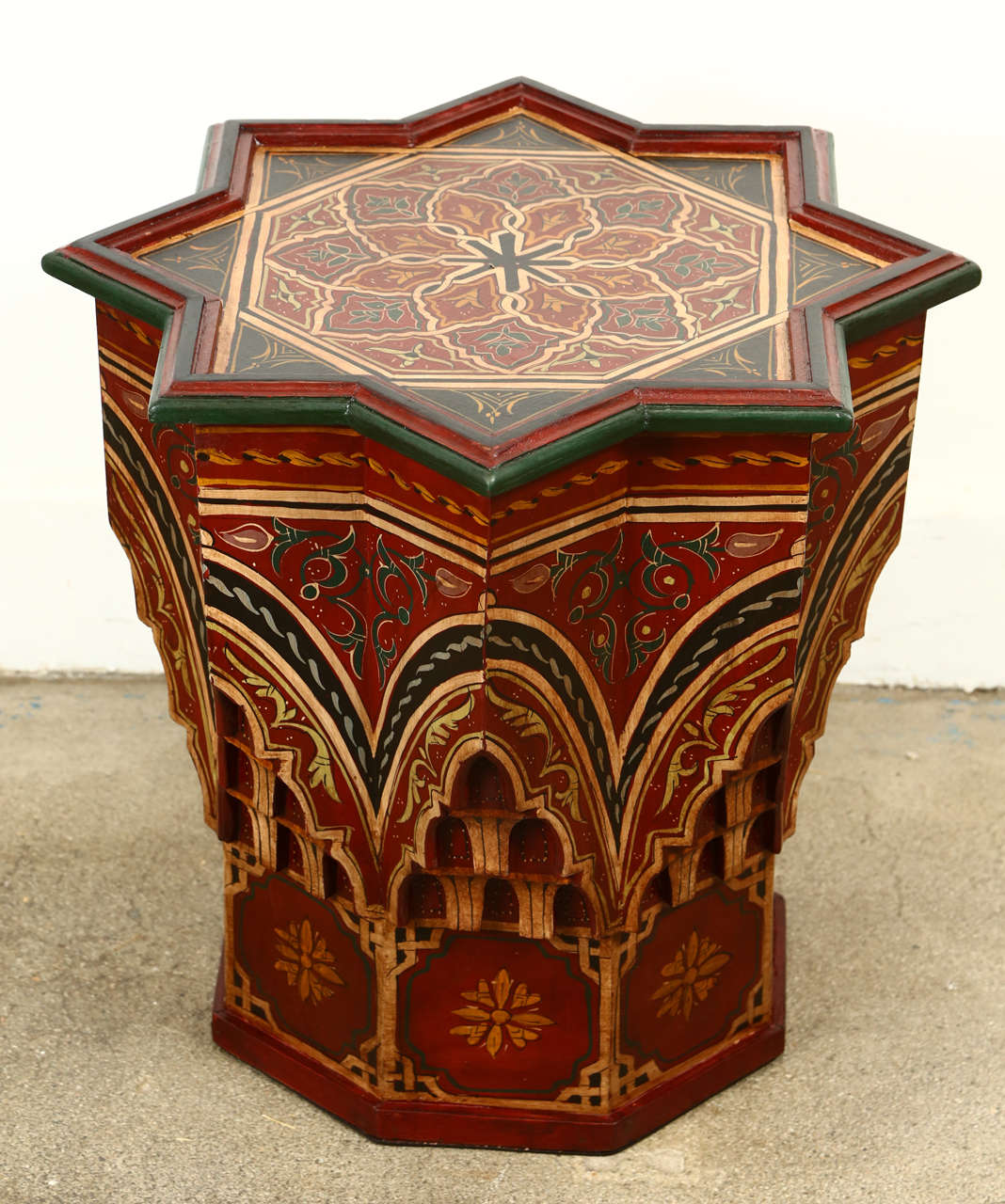 Moroccan colorful hand-painted and carved side occasional table with Moorish designs.
Hispano Moresque style in maroon background color with multicolored floral and geometric designs. 
Very decorative fine artwork on a star shape base.
You can