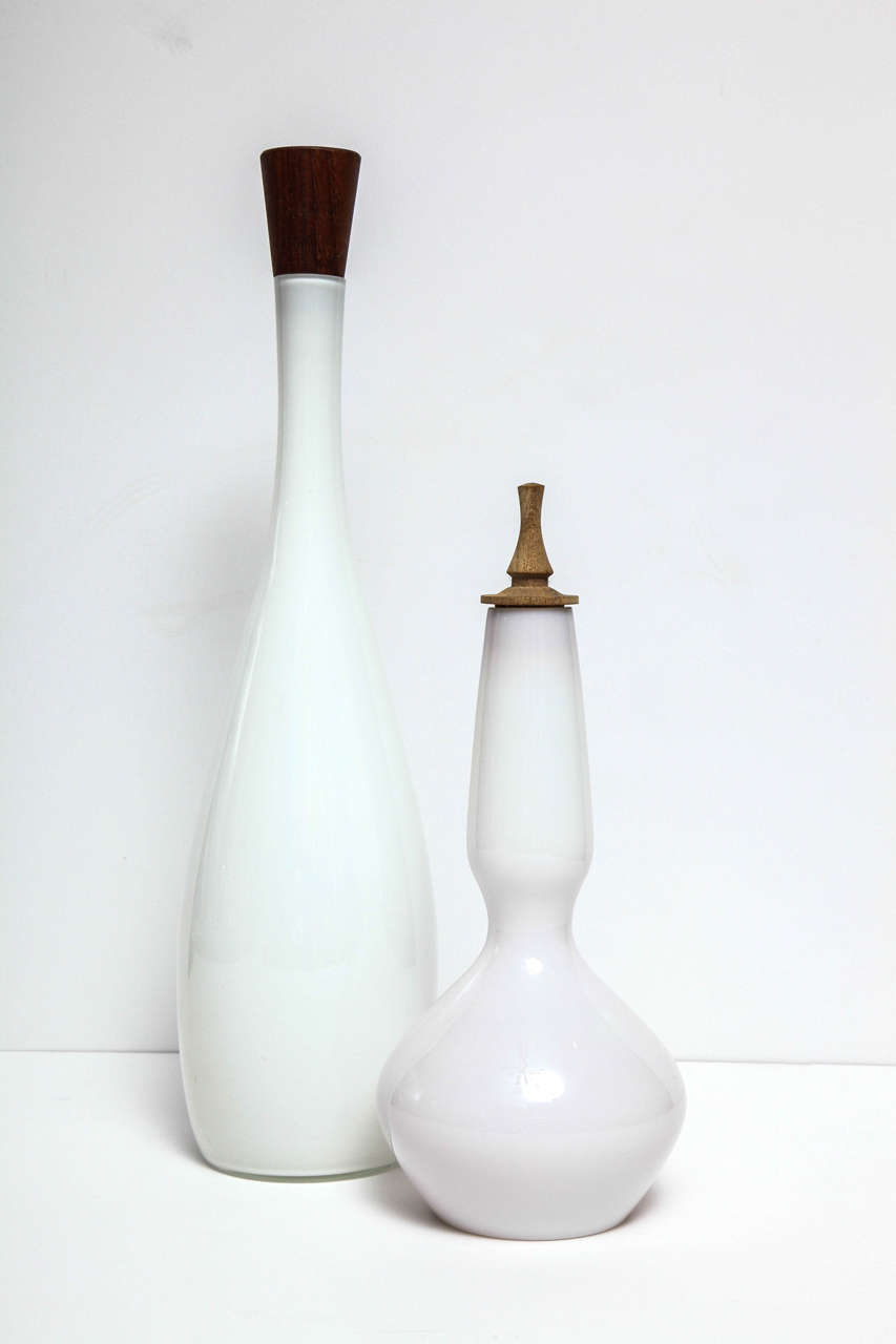 Decorative white, Mid-Century Modern glass bottle by Holmegaard, circa 1960, with a wood stopper. The white bottle is on the right side in the picture. Made in Denmark.
Taller bottle is sold.