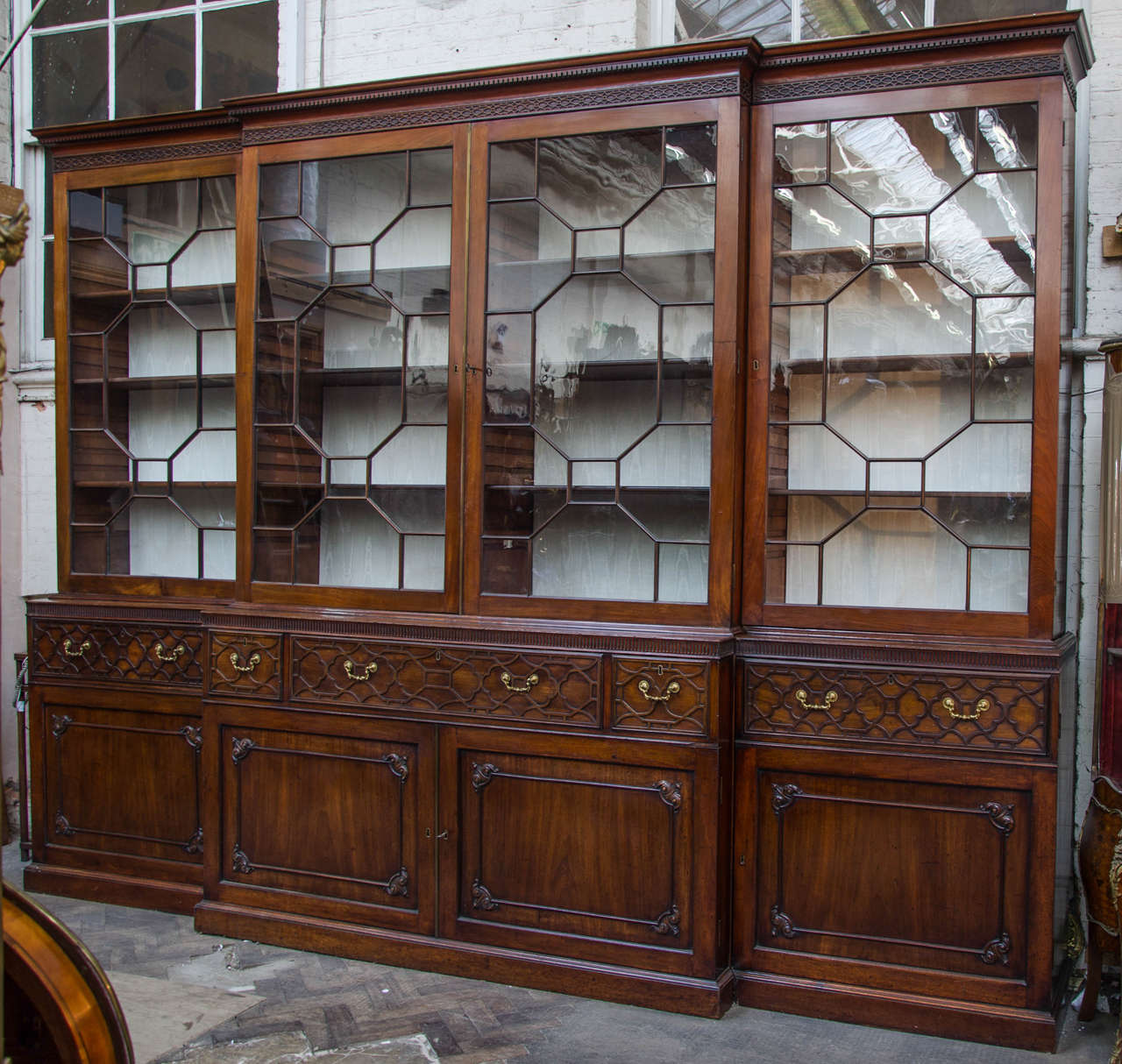 An important and very impressive 18th century Chippendale period mahogany break fronted bookcase, having dental moulding to the cornice, astragal glazed doors above three large frieze drawers, each with gothic blind fret and the original gilded drop