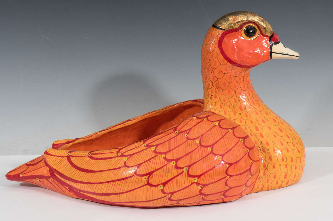 A vintage papier mâché planter, in the form of a duck, hand-painted in brilliant oranges and yellows, with glass eyes, produced circa 1970s by Mexican artist Sergio Bustamante. Good vintage condition, with minor chips to the finish from previous