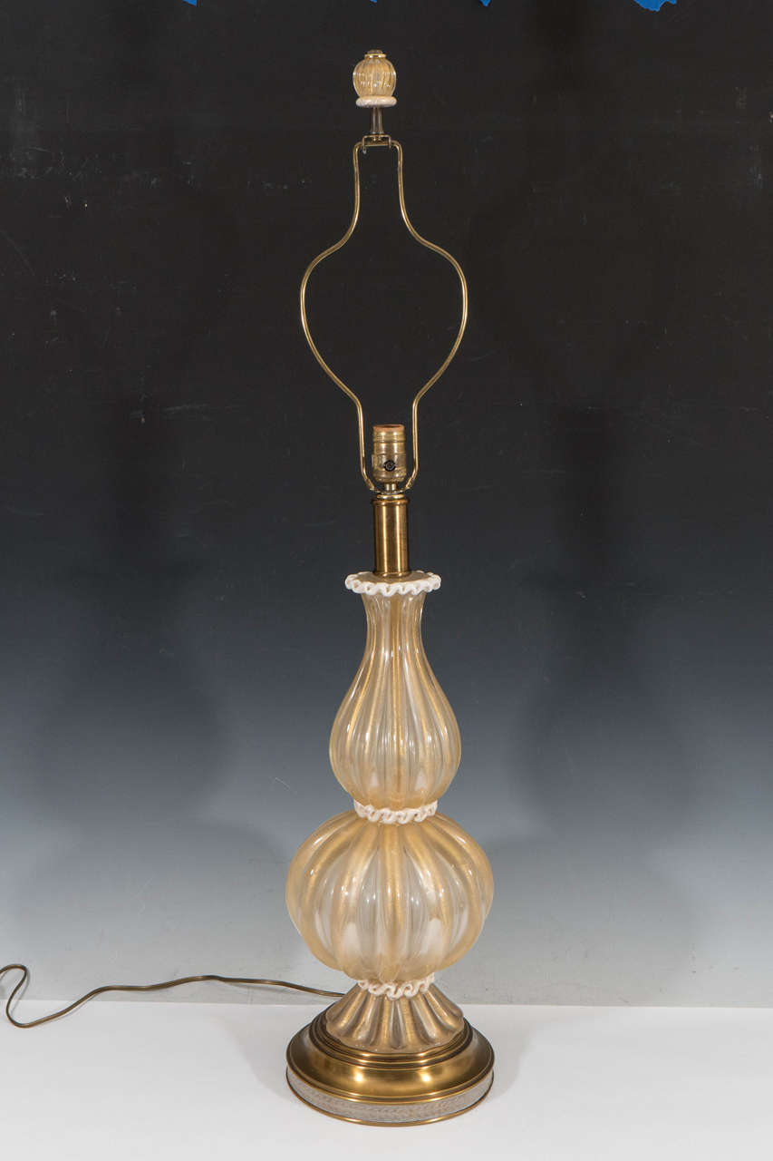 A vintage pair of Barovier & Toso Murano glass table lamps, with gold inclusions and gadrooned stems, waisted by three bands of lattimo glass, stylized as frilled trimming, on a circular brushed brass foot; matching glass finial and harp included.