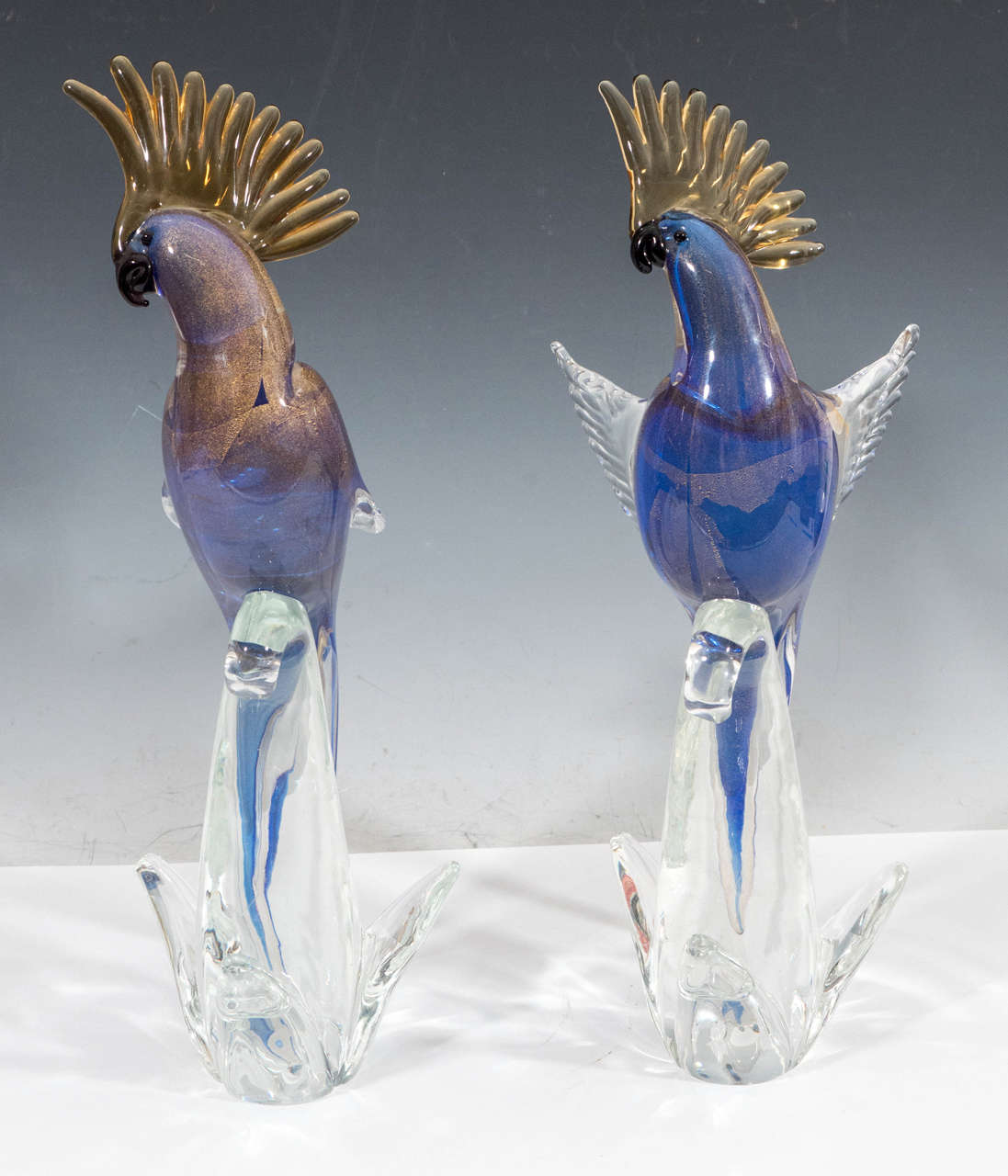 A vintage pair of Murano glass sculptural cockatoo parrots, in indigo with gold inclusions, rendered through 'Sommerso' technique, each perched on transparent curved base, by Archimede Seguso. Both pieces are in good vintage condition, with age