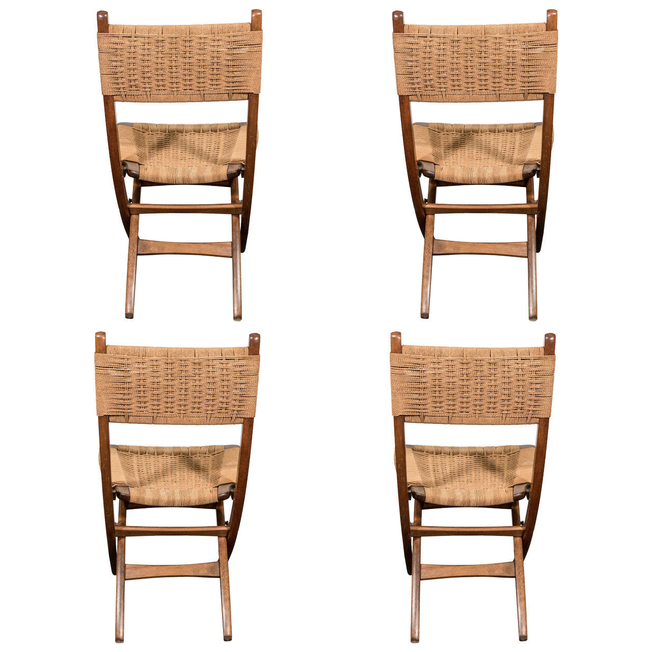 A vintage set of four folding chairs in the Scandinavian Modern style and inspired by designer Hans Wegner, with braided paper-cord backs and seating against wooden Campaign frames on X-form legs. Markings include stamp [Yugoslavia]. Good vintage