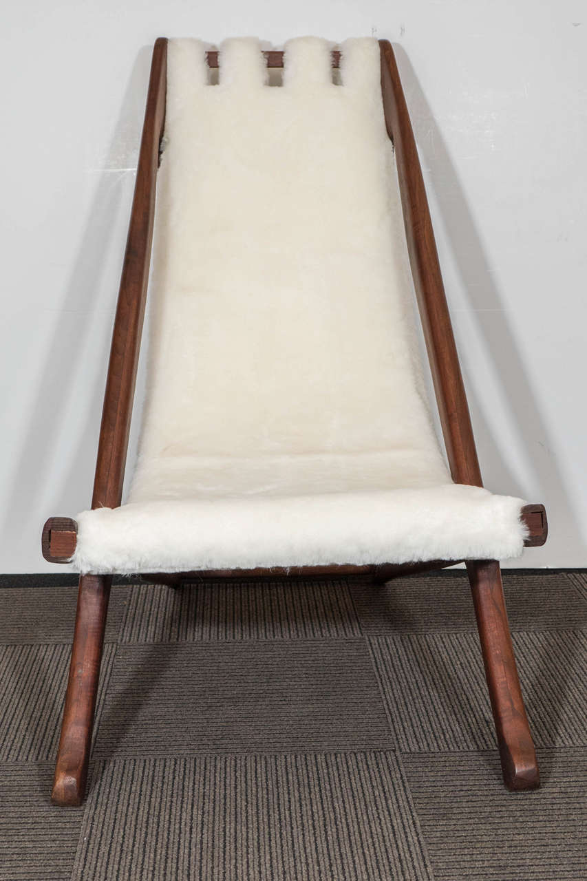 A vintage Scandinavian modernistic sling back lounge chair, with carved rosewood frame and newly upholstered in sheepskin. Good vintage condition, consistent with wear and age.