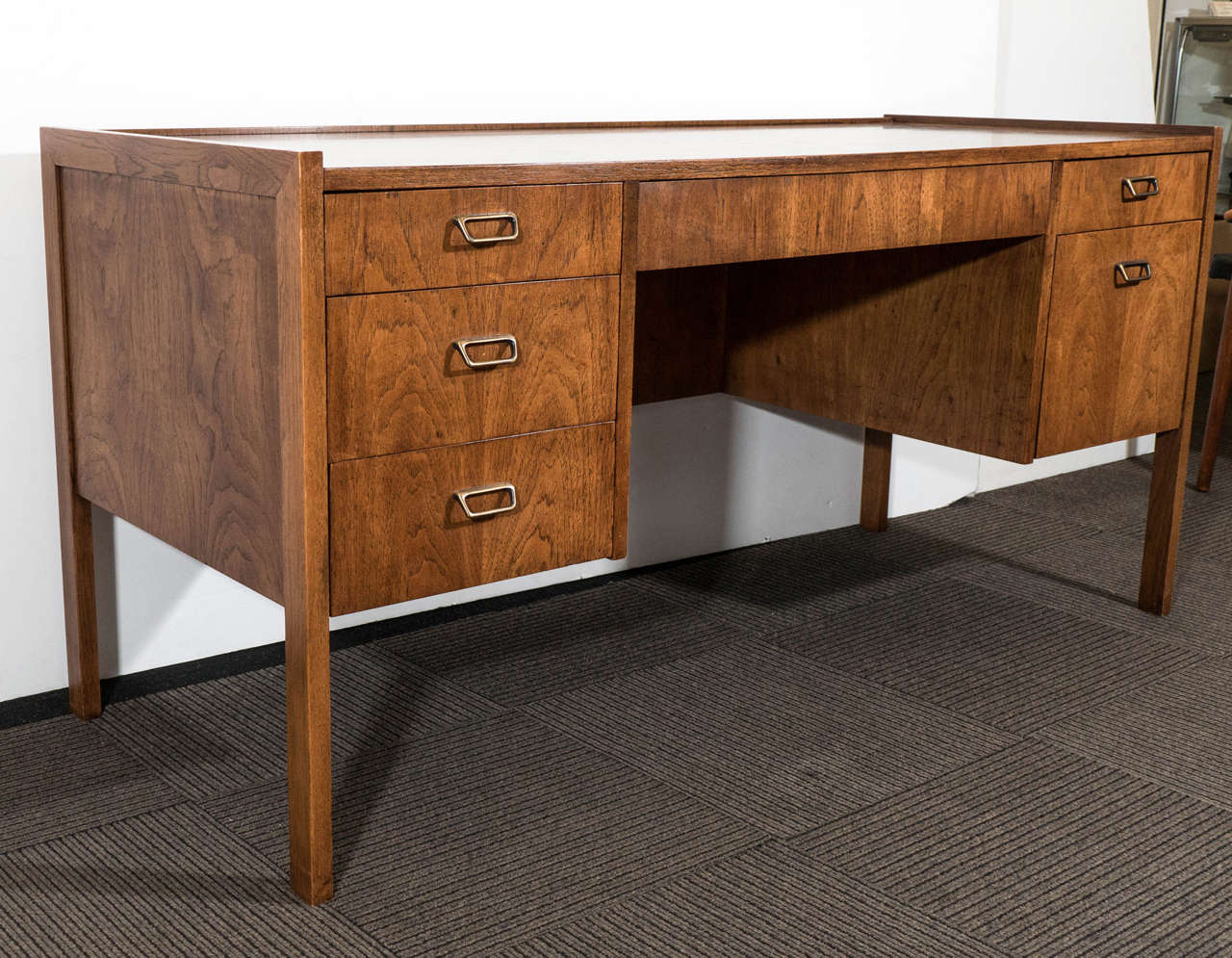 A vintage six-drawer modern executive desk by Founders Furniture Company, produced circa 1960s-1970s, veneered in walnut with square brass handles. Good vintage condition, with some age appropriate wear.