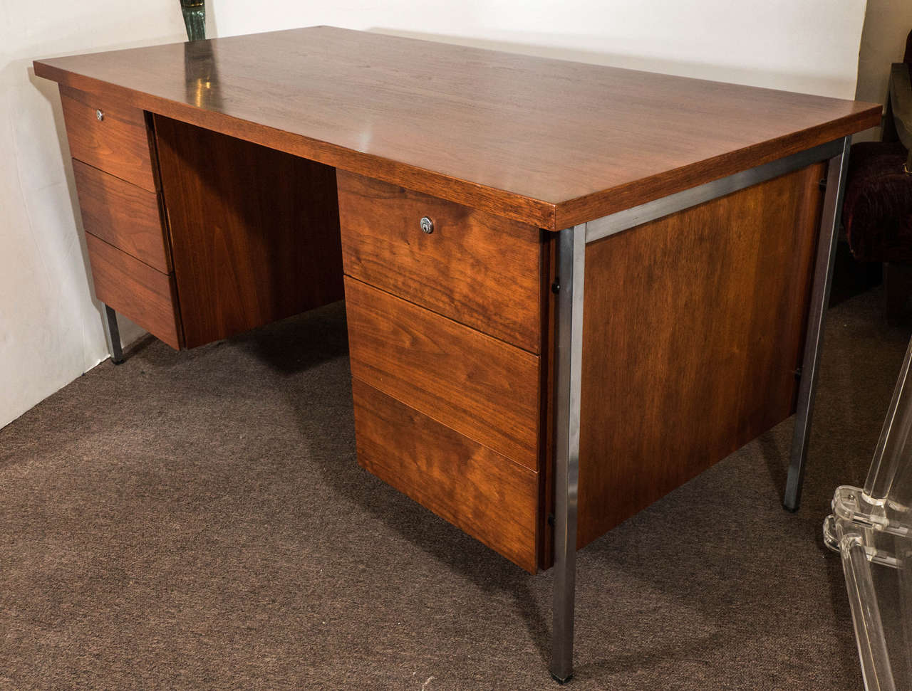 A office desk by architect Florence Knoll, in walnut, with six drawers on rectangular chrome legs, circa 1960s. Markings include original label [Knoll Associates Inc.]. Good vintage condition with some age appropriate wear on the chrome legs.