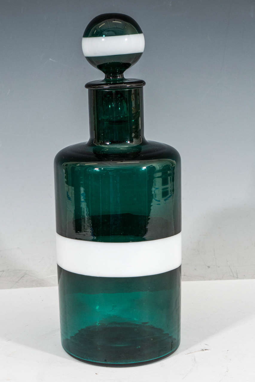 A vintage hand-blown, cylindrical art glass decanter, produced, circa 1950s, with round finial stopper in transparent green with two bands of white 'lattimo'. Marks include original label and etched signature. Good vintage condition with some age