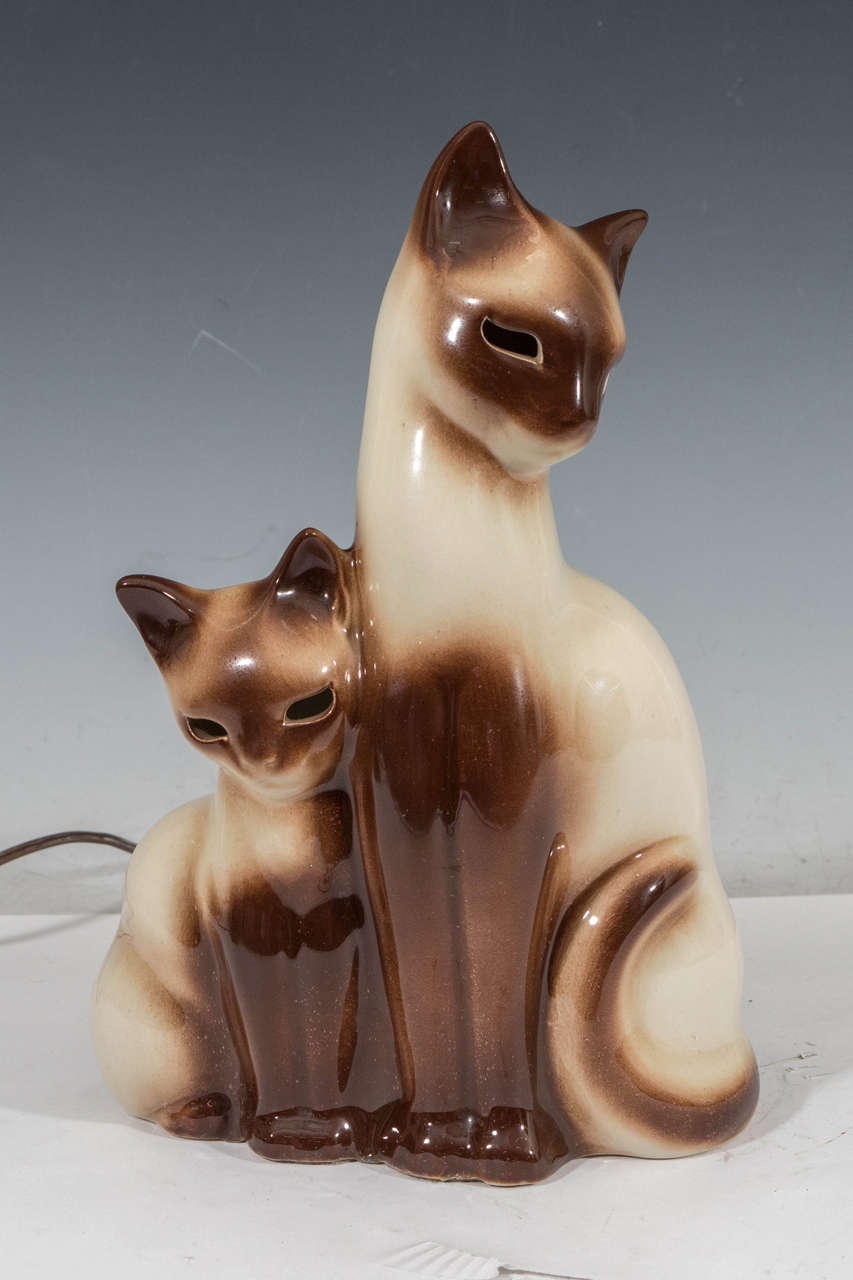 A vintage pair of TV lamps, with Siamese cat and kitten, produced circa 1950s by designer Howard Kron for Texans Inc. Wiring and sockets to US standard, each requiring one Edison base bulb. Signed on back by artist [® Kron] and one of pair stamped