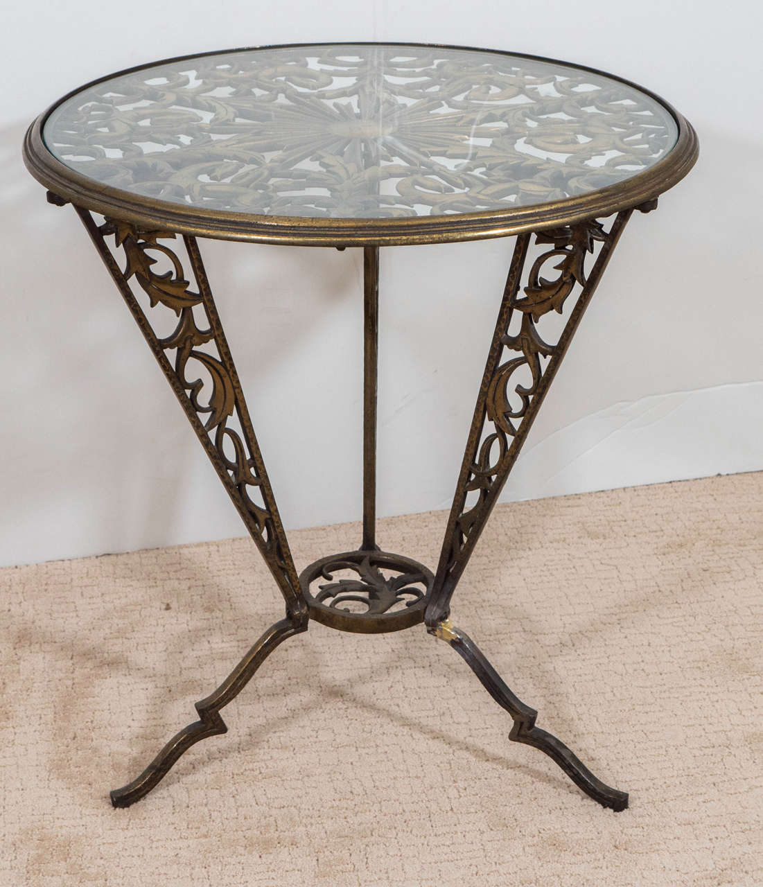 A vintage pair of Art Deco occasional tables in gilded wrought iron, produced circa 1930s by Karl Hagenauer for Rena Rosenthal, with brass-plated circular frame, inset with glass table top, supported by decorative plate, with circling equestrian