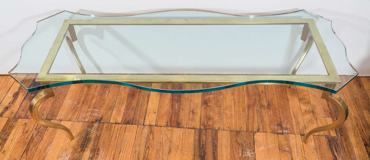 A circa 1940s coffee and cocktail table in the Hollywood Regency style, with serpentine glass top on brass frame and cabriole legs. Very good vintage condition, with some age appropriate wear and minor scratches to legs.
