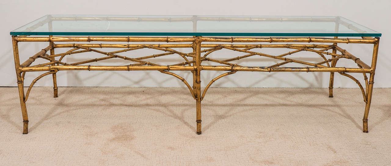 A vintage gilded metal coffee table, in the chinoiserie style, with glass top on faux bamboo legs and bracket stretcher. Good vintage condition with some age appropriate wear.