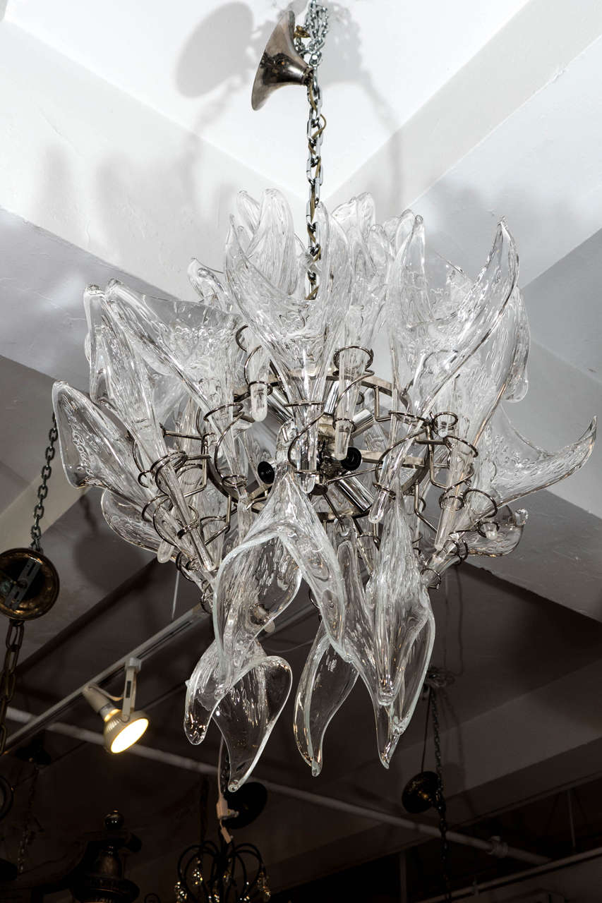 A vintage Murano glass chandelier, produced circa 1970 - 1980, consisting of individually hand-blown 'pulegoso' glass flames, which slip into chrome-plated spiral holders, four of which hang as drops, affixed to a chrome-plated nucleus. Wiring and