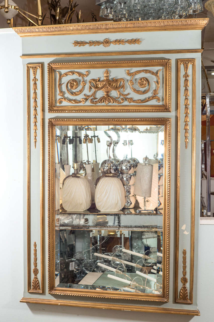 A vintage Italian trumeau wall mirror designed in the neoclassical mode, produced, circa 1960s, the glass set in an architecturally styled, pale green and giltwood frame, with classical motifs of scrolling foliates, bell flowers and anthemions. Good