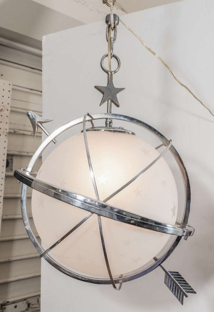 A vintage Art Deco Celestial Globe with Arrow Pendant Light by Lurelle Guild for Chase, produced circa 1930s, in the style of a celestial globe in frosted glass, etched with stars, surrounded by four crossing chrome bands, a stylistic piercing arrow
