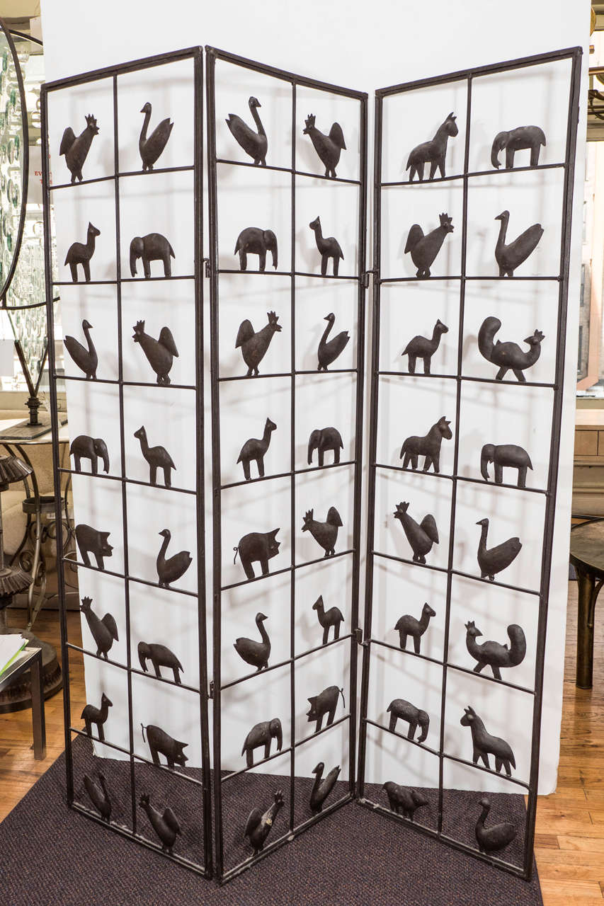 A wrought iron, antiqued room divider, each square space occupied by a variety of cut-out and soldered animal shapes. Good condition with age appropriate wear.
