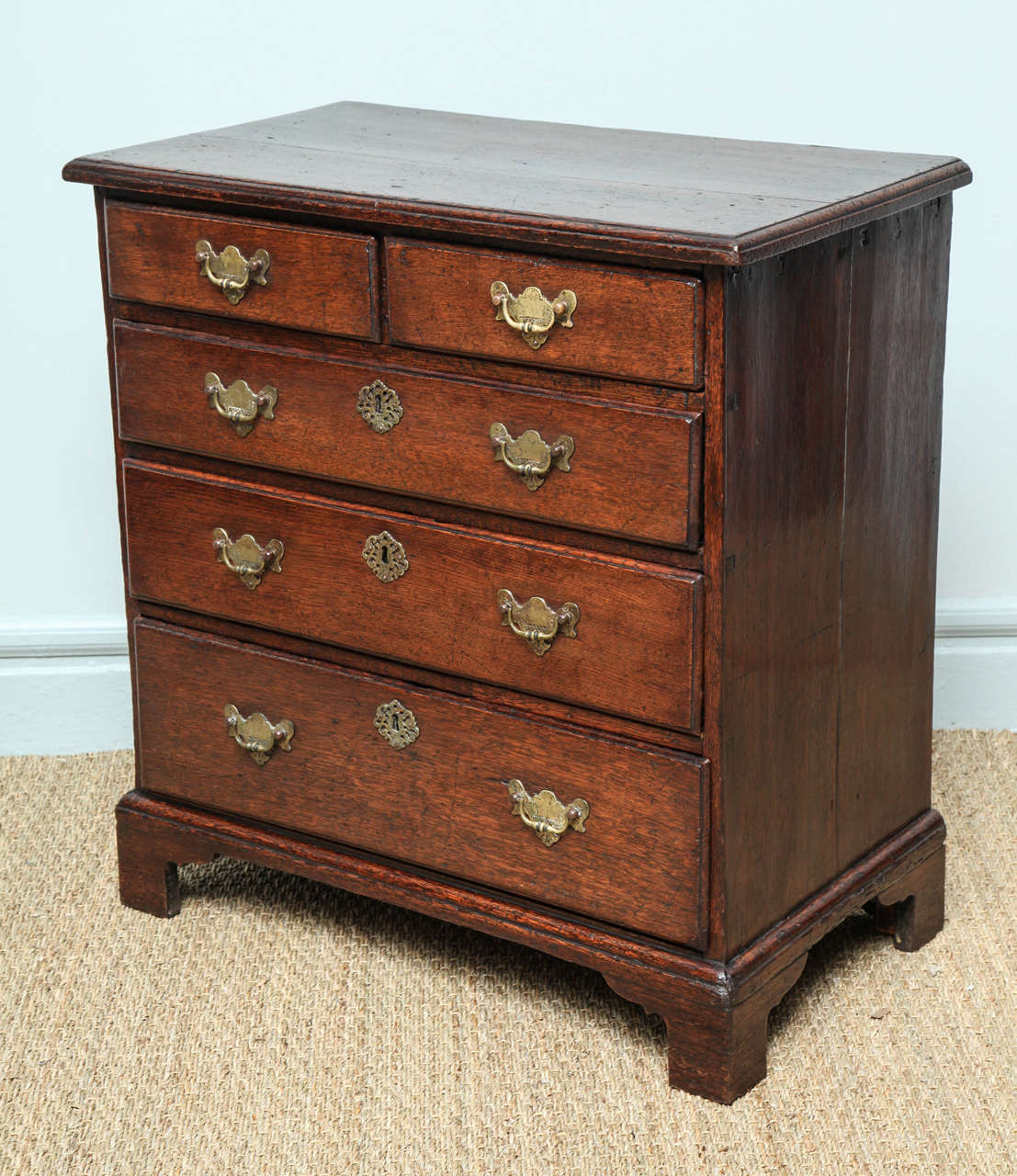 Very fine George I period oak bachelors chest, the single plank top over two short and three wide drawers, all with original etched brasses. standing on bracket feet, the whole with rich pleasing color and in excellent condition.