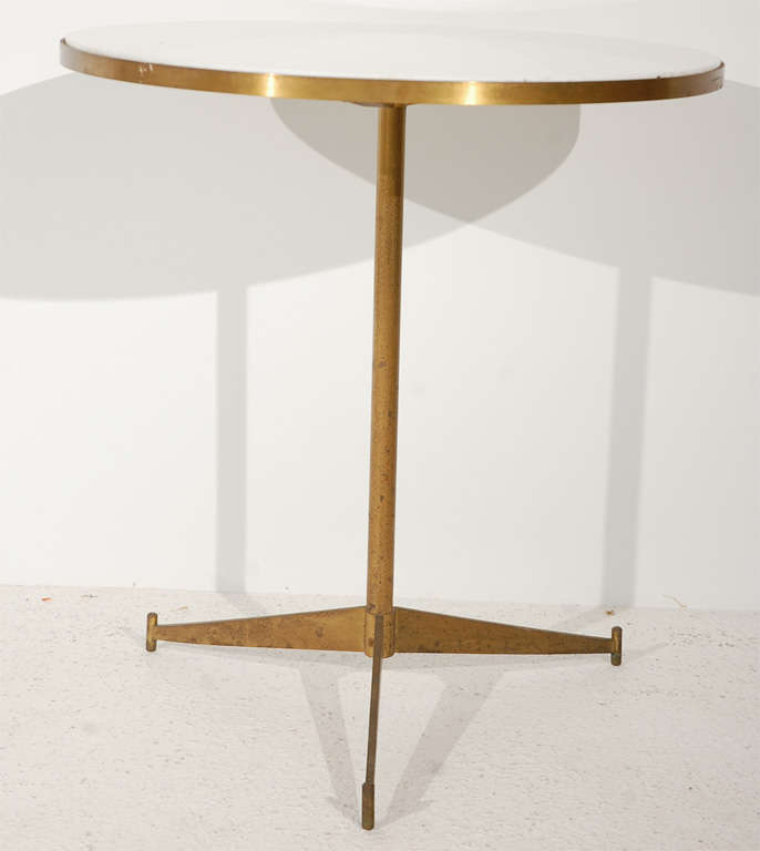 Paul McCobb's classic model no. 1094 cigarette table features an opaque white glass top banded in brass on a  tripod base.