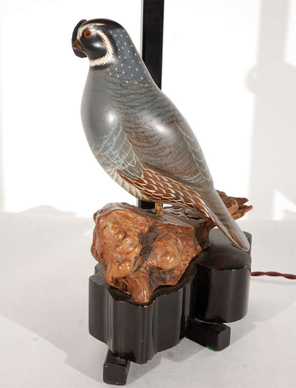 A unique avian table lamp by William Haines from the estate of Ted Graber. The lamp features a carved wood hand-painted quail perched on a piece of driftwood and set atop an irregular-shaped wood base. The lamp has on-off switches on the base and