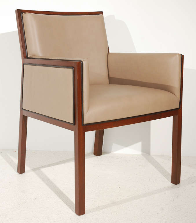 A chic, leggy wood-framed armchair, newly upholstered in taupe leather and piped in a contrasting black leather.