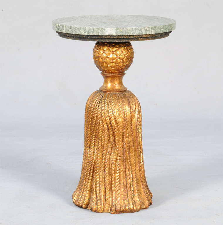 Accent table, having a gilded base of metal cast as an oversized tassel, with round marble top.
