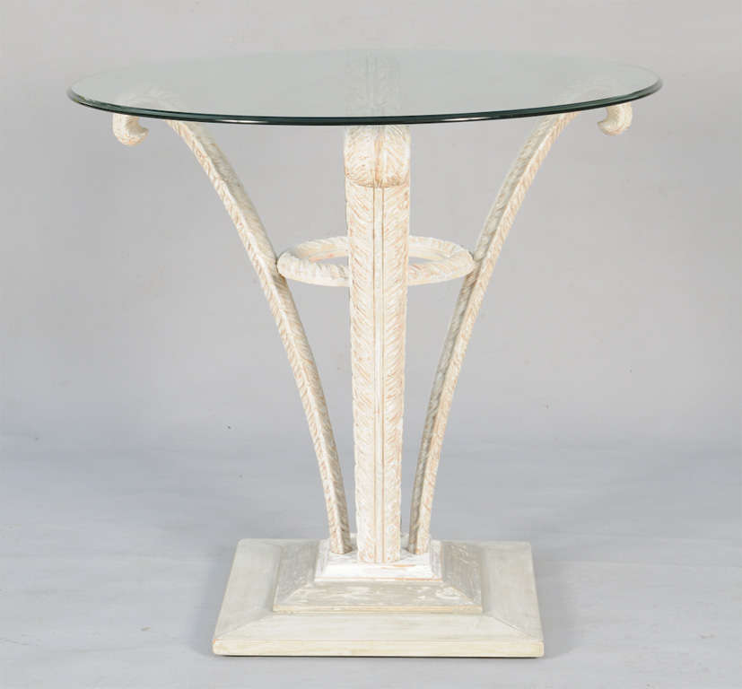 Occasional table, having a round top of glass, raised on four legs carved as Prince-of-Wales plumes having a pickled finish, joined by gadrooned ring stretcher, on graduated plinth base.