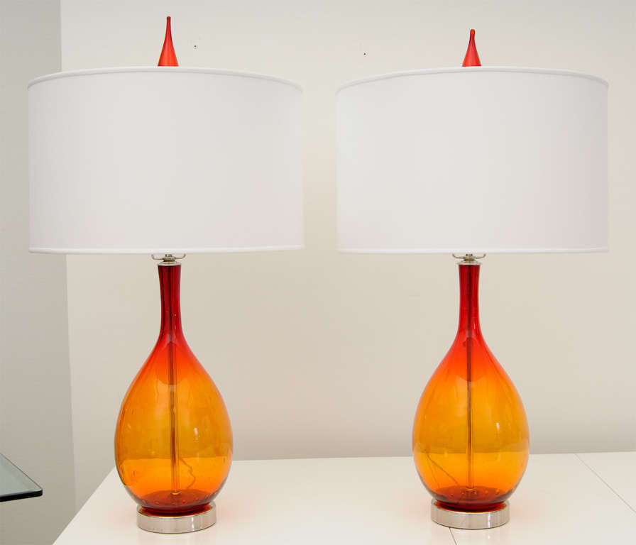 Finely blown orange to red glass lamps with original vintage harps complete with glass stopper finials. Glass has bubble design visible in image 4 and lamps have been professionally cleaned and rewired with chrome appointments. Sold as a pair with