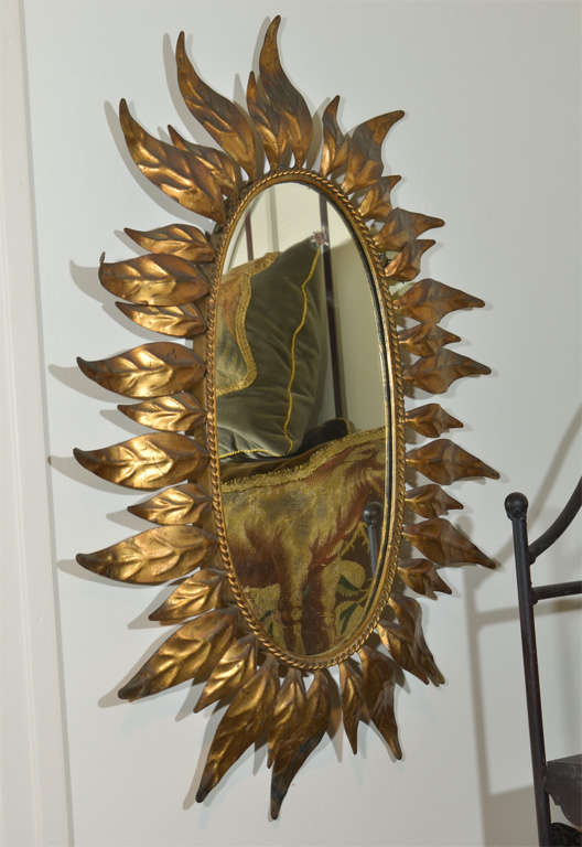 France, 19th Century Oval Sunburst Mirror. This beautiful gilded mirror has stylized leafs forming the three dimensional frame. It's the perfect size to stand alone over a small piece of furniture, or to cluster in a collection across an entire