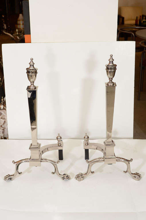 Exceptional pair of tapering rectangular form polished nickel andirons with stylized urn finial tops and claw and ball feet.