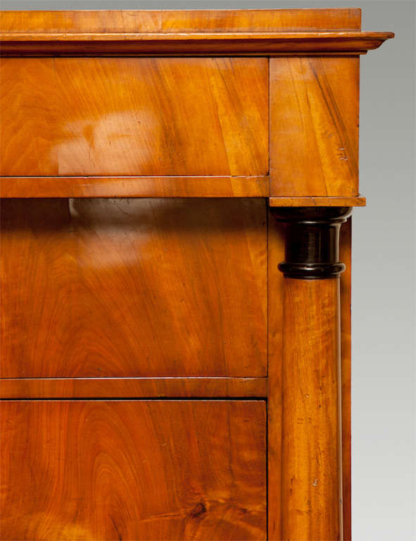 Biedermeier fruitwood semanier.  Overhanging top drawer above six flush-mounted drawers flanked by columns with ebonized bases and capitals ending in square feet.  Circa 1820-30.