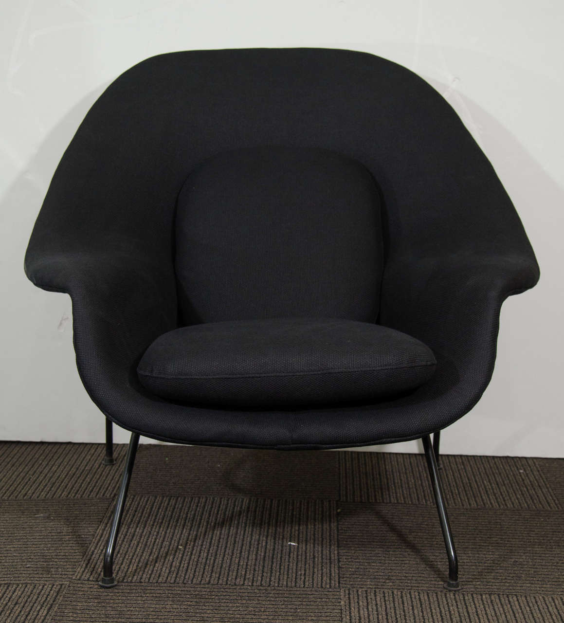 A vintage 1950s Womb chair and ottoman by Eero Saarinen for Florence Knoll. Created with foam molded over a fiberglass shell, the chair and ottoman have black lacquered metal legs. Newly reupholstered in black basket weave linen.  Loose cushions on